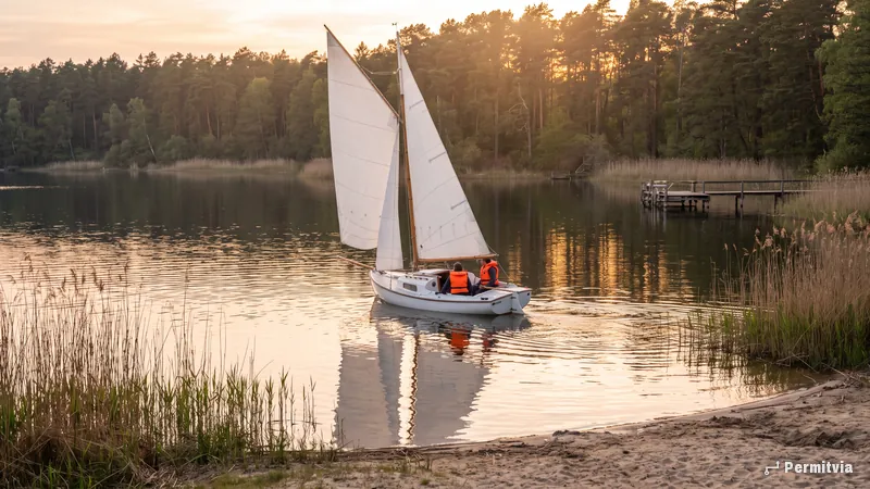 Segelboot im Abendlicht auf einem Brandenburger See mit Schilf und Kiefernwald